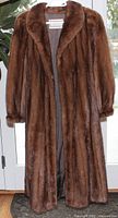 Front view of full-length brown fur coat on hanger
