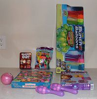 All items grouped on countertop: Bunch O Balloons pack, Sushi Go! tin, bag of balloons, two matching game boxes, pink ball, two purple maracas