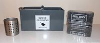 grey metal cleaning caddy, two wrapped grill bricks, stainless perforated holder