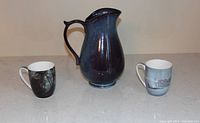 Front view of ceramic pitcher and two mugs
