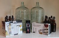 Full lot with two glass carboys, swing-top bottles, boxed cooler, aerator, corkscrew