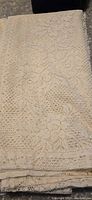 Folded ivory lace curtain panel close-up showing pattern