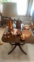 Overall view of copper items on table including lamp, pots, dish and accessories