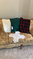 All linens displayed on sofa: cream lace, green damask, plaid tablecloth, white centerpiece