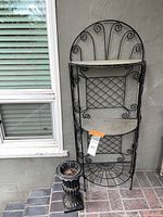 Full view of wrought iron shelf with planter at base