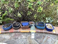 Row of eight blue ceramic bonsai pots and Buddha on wall