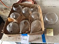 Cardboard box containing eight glass and one plastic clear globes with hanging loops