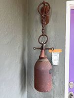 Full view of hanging iron bell with bracket, chain and tag