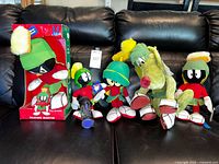Group shot of all five plush including boxed Talking Marvin, three unboxed Marvin figures, and K-9 dog on couch