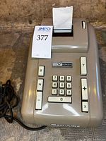 Full view of Remington adding machine with power cord and paper roll