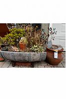 Overall view showing half barrel with succulents, clay pot, metal art