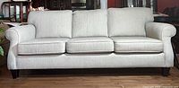 Front view showing entire sofa with three cushions and rolled arms