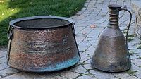 Cauldron and ewer side by side on stone path showing overall form and patination