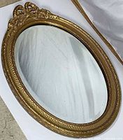 Front view of oval gilt mirror showing overall design and crest