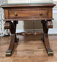 Front view highlighting drawer, carved legs, brass-tone caps