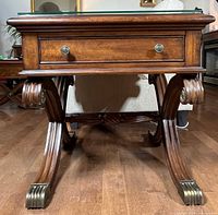 Front view showing glass top, drawer, carved legs, brass foot caps