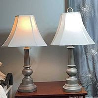 Both matching lamps side by side on table, shades illuminated