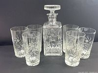 Crystal decanter with stopper flanked by six highball glasses