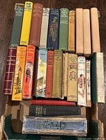 Group of assorted antique books in open carton showing spines and covers