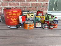 Group shot of gasoline can, multiple automotive tins and spout