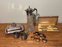 Group shot of all items: carafe, covered dish, pewter cream and sugar, napkin rings, boxed utensil set