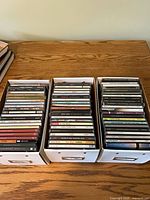 Three boxes filled with rows of CD jewel cases