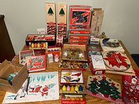 Overview of entire lot on table showing ornaments, lights, candles, plates, tin, books and placemats