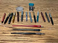 Group shot of 13 fountain pens, 3 dip pens, glass stamp roller and jar of nibs