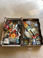 Two boxes filled with assorted electrical components, hardware, garden hose fittings