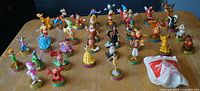 Full lot of 35 Disney figures on table with one sealed bag visible