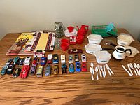 Full lot overview on table showing vehicles, books, marbles, kitchenware
