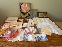 Full lot view of linens, towel set, book and plaque on table