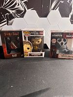 Front view of all three boxed figures: Trick 'r Treat Sam, Funko Pop! Leatherface #1150, Handmade by Robots Ghost Face