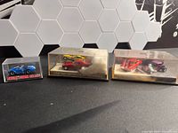 Three acrylic cases containing five Hot Wheels cars
