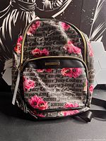 Front view showing floral logo fabric, front zip pocket, brand plaque