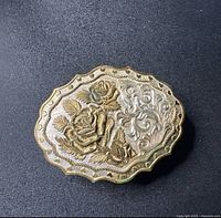 Front view showing floral gold-tone roses and silver-tone engraved background