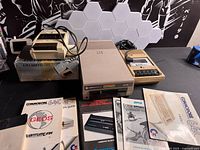 Group shot showing Commodore 1541 drive, C2N datasette, Atari recorder, assorted manuals