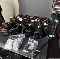 Multiple wireless handheld barcode scanners with USB receivers, finger scanners, cables and one wired scanner visible on tabletop