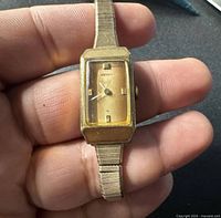 Front view of Seiko rectangular gold-tone watch in hand
