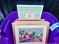 Multiple framed needlework pieces in purple tote