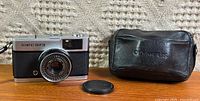 Front view of Olympus Trip 35 camera with lens cap and case