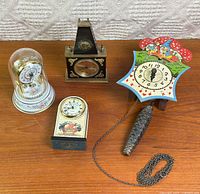 Group shot of four clocks and pine-cone weight