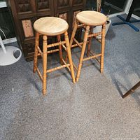 Two wooden bar stools beside cabinet showing overall design