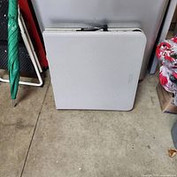 4-ft folding table folded for storage, beige top visible