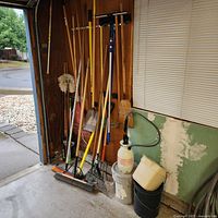 Group of yard tools leaning against garage wall