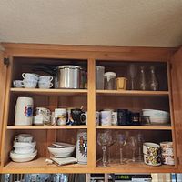 Cabinet overview showing Pyrex cups, stainless pot, mugs, bowls, glassware