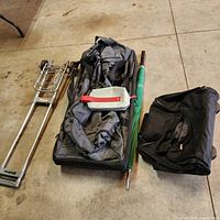 All four items laid out: folding cart, grey duffel, green umbrella, black carry-on