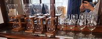 Four Kwak glasses on wooden stands and six etched wine glasses displayed together