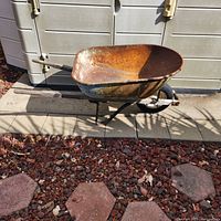 Side view of metal wheelbarrow showing basin, frame and tire