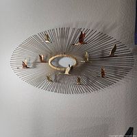 Full view of metal sunburst wall sculpture showing birds and central oval